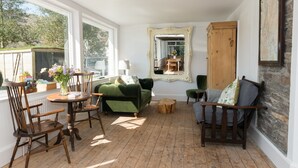 Une pièce chaleureuse avec un canapé vert, des chaises en bois, un meuble en bois et un grand miroir.