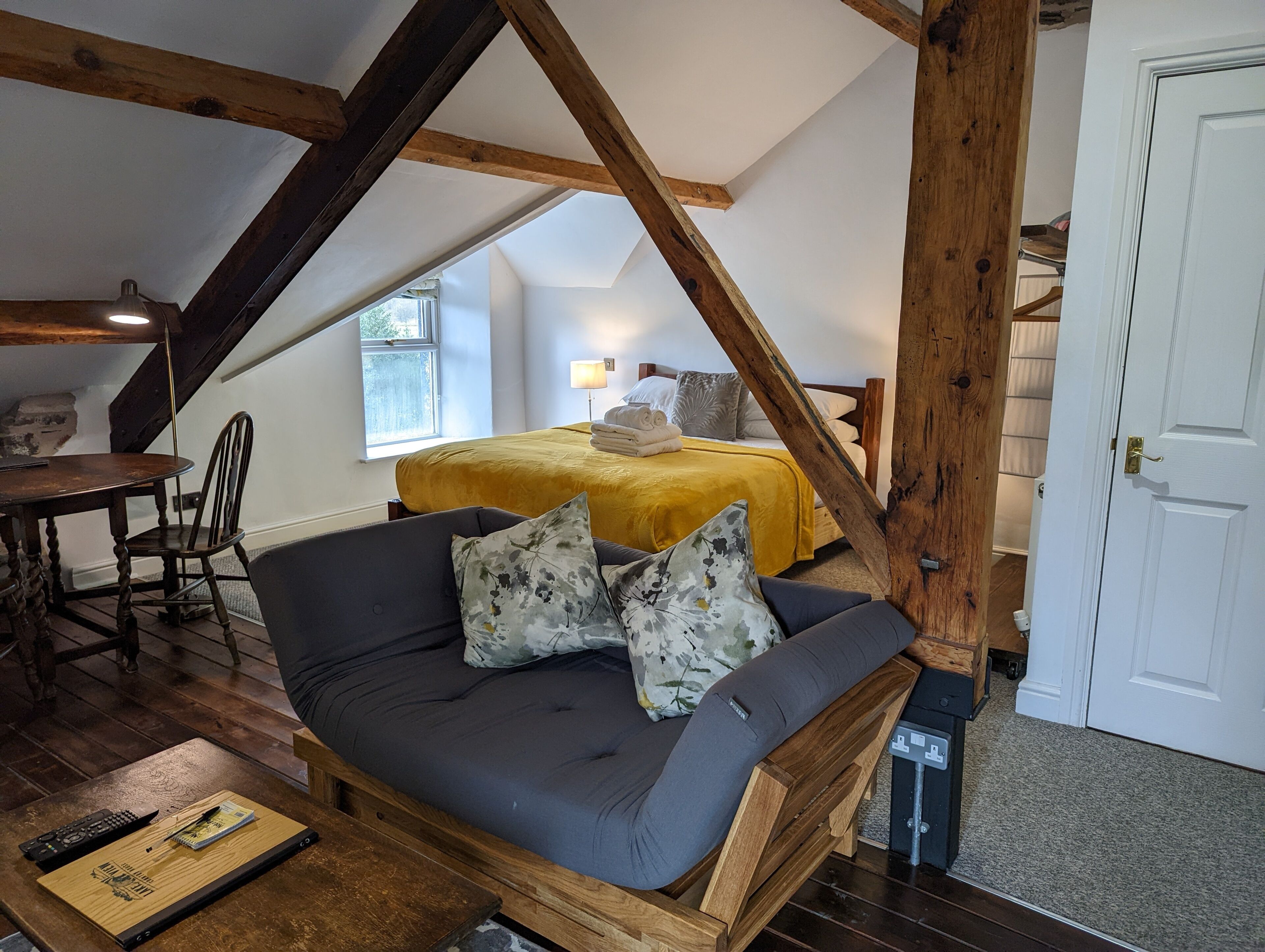 Et soveværelse i loftstil med seng, sofa og spiseplads.