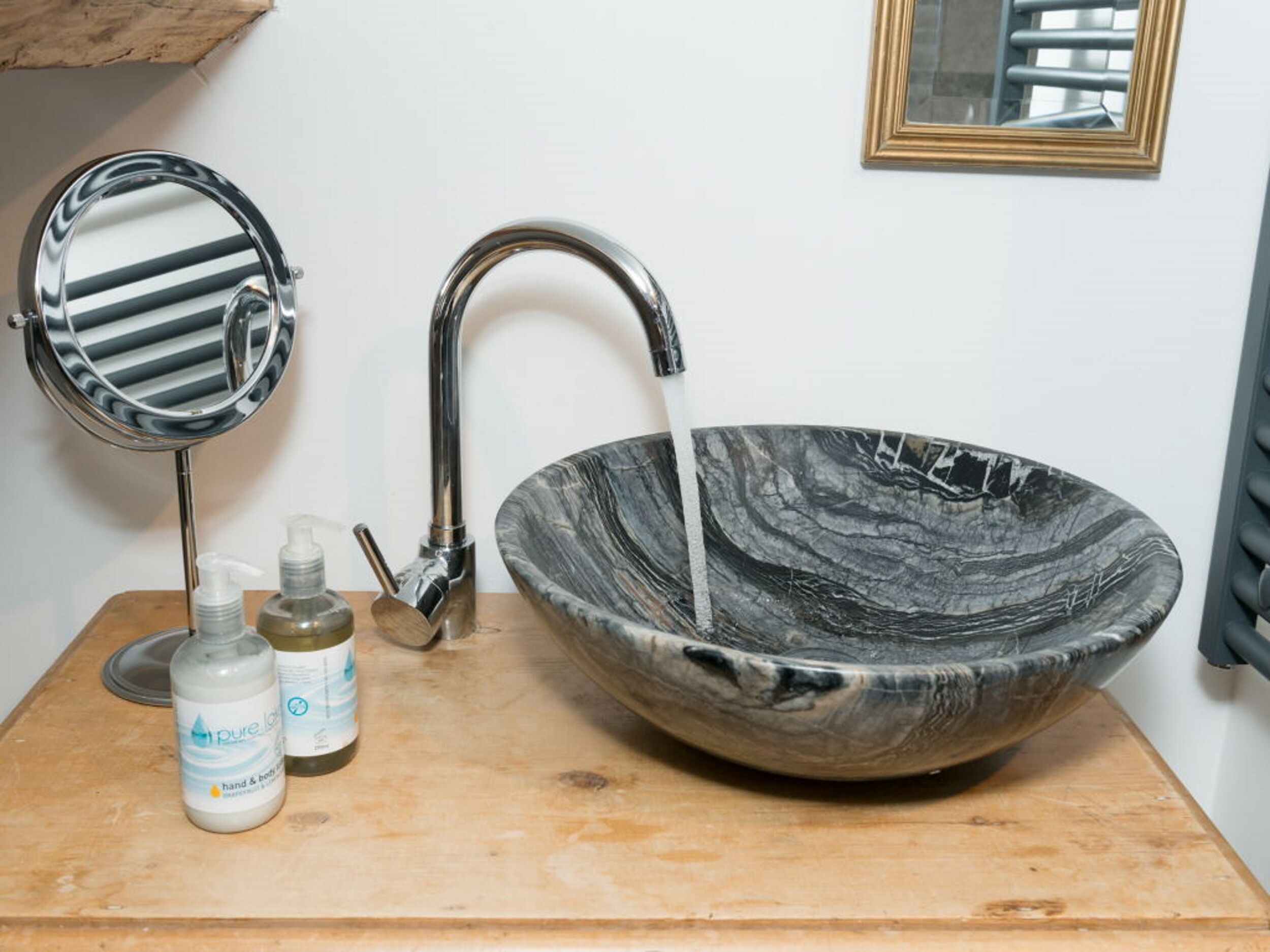 A bathroom with a marble sink, a mirror, and two bottles of hand soap.