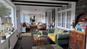 Un salon chaleureux avec une cheminée, des fauteuils confortables et une bibliothèque remplie de livres.