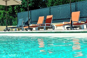 Una piscina al aire libre, sillones reclinables de piscina