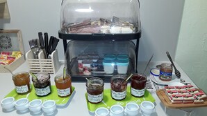 A buffet table with various food items, including jars of jam and a display of macarons. - Hôtel du Viaduc (Tarascon)