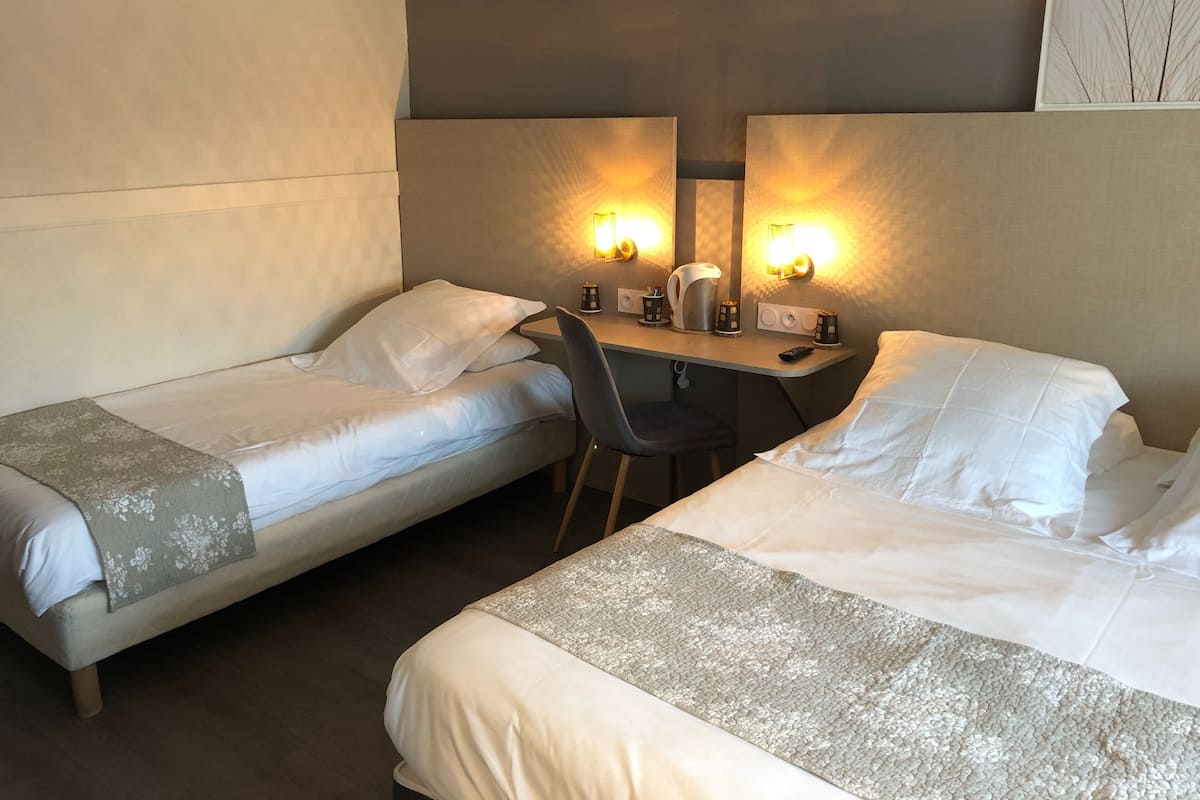 Ein Hotelzimmer mit zwei Einzelbetten, einem Schreibtisch mit Stuhl und einem Spiegel über dem Schreibtisch.