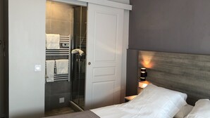 A hotel room with a bed, a walk-in closet with towels, and a bedside lamp. - Hôtel du Viaduc (Tarascon)
