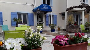 A hotel exterior with a blue awning, outdoor seating, and potted plants. - Hôtel du Viaduc (Tarascon)