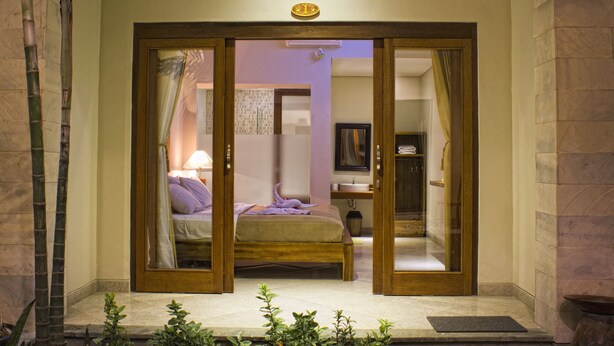 A hotel room with a bed, a bathroom, and a small sitting area. - Sura Inn Ubud (Ubud)