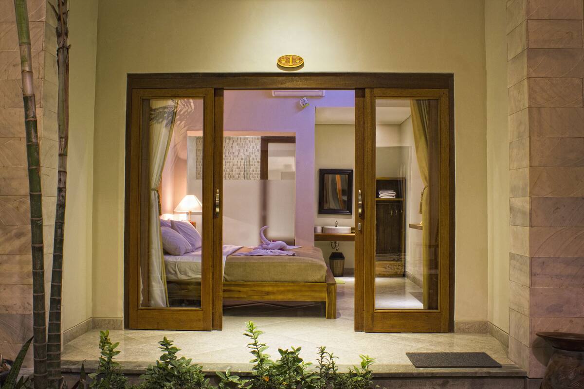 Quarto de hotel com uma cama, banheiro e um pequeno espaço de estar.