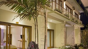 A hotel with a large entrance, a balcony with plants, and a statue in the foreground. - Sura Inn Ubud (Ubud)