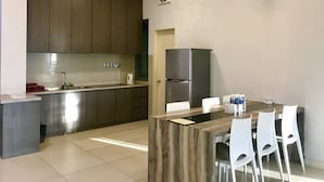 A modern kitchen with dark wooden cabinets, a stainless steel refrigerator, and a dining area with white chairs and a wooden table.