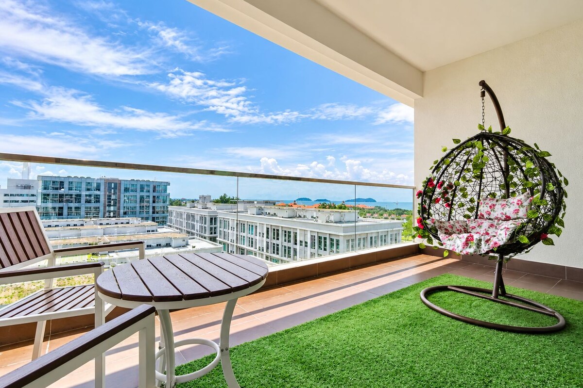 Ein Balkon mit Hängesessel, kleinem Tisch und Kunstrasen.