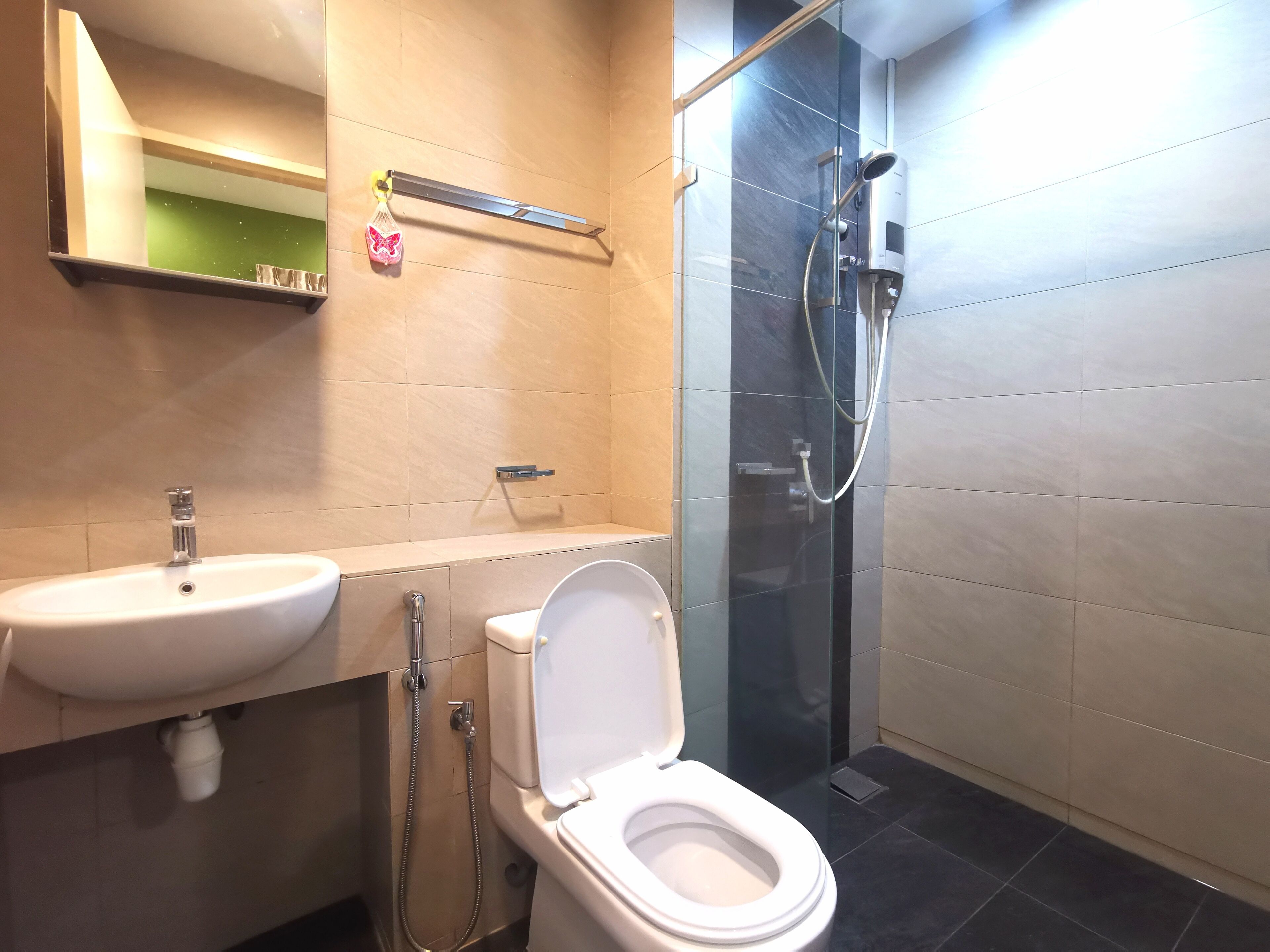 Egy modern fürőszoba mosdókagylóval, WC-vel és üvegfalas zuhanyzóval.