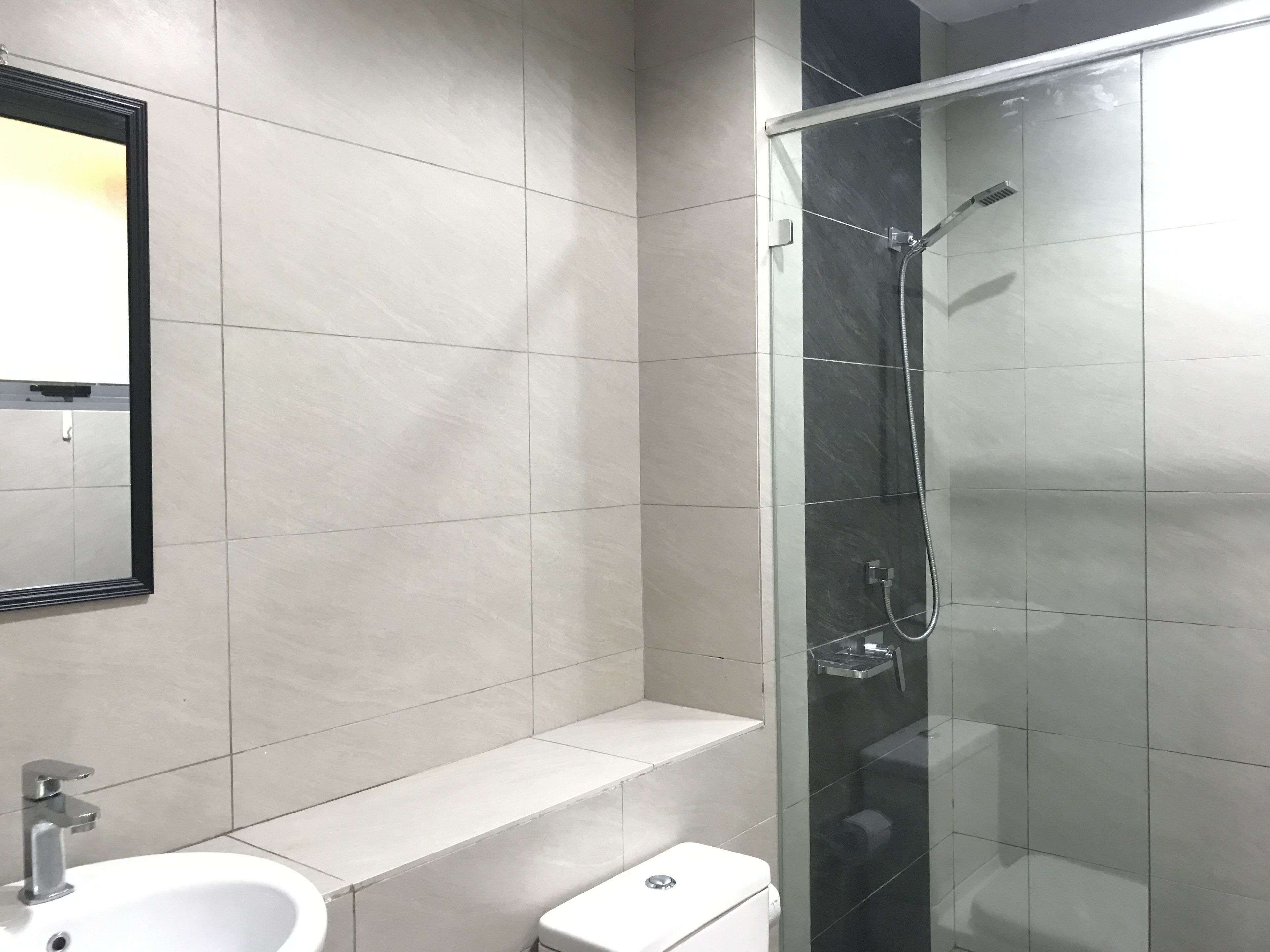 Un baño moderno con cabina de ducha de vidrio, un lavabo blanco y un inodoro.