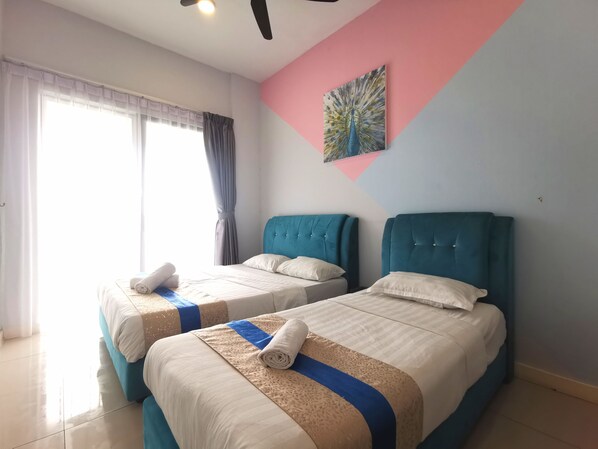Habitación de hotel con dos camas, un ventanal con cortinas, ventilador de techo y decoración de pared colorida.