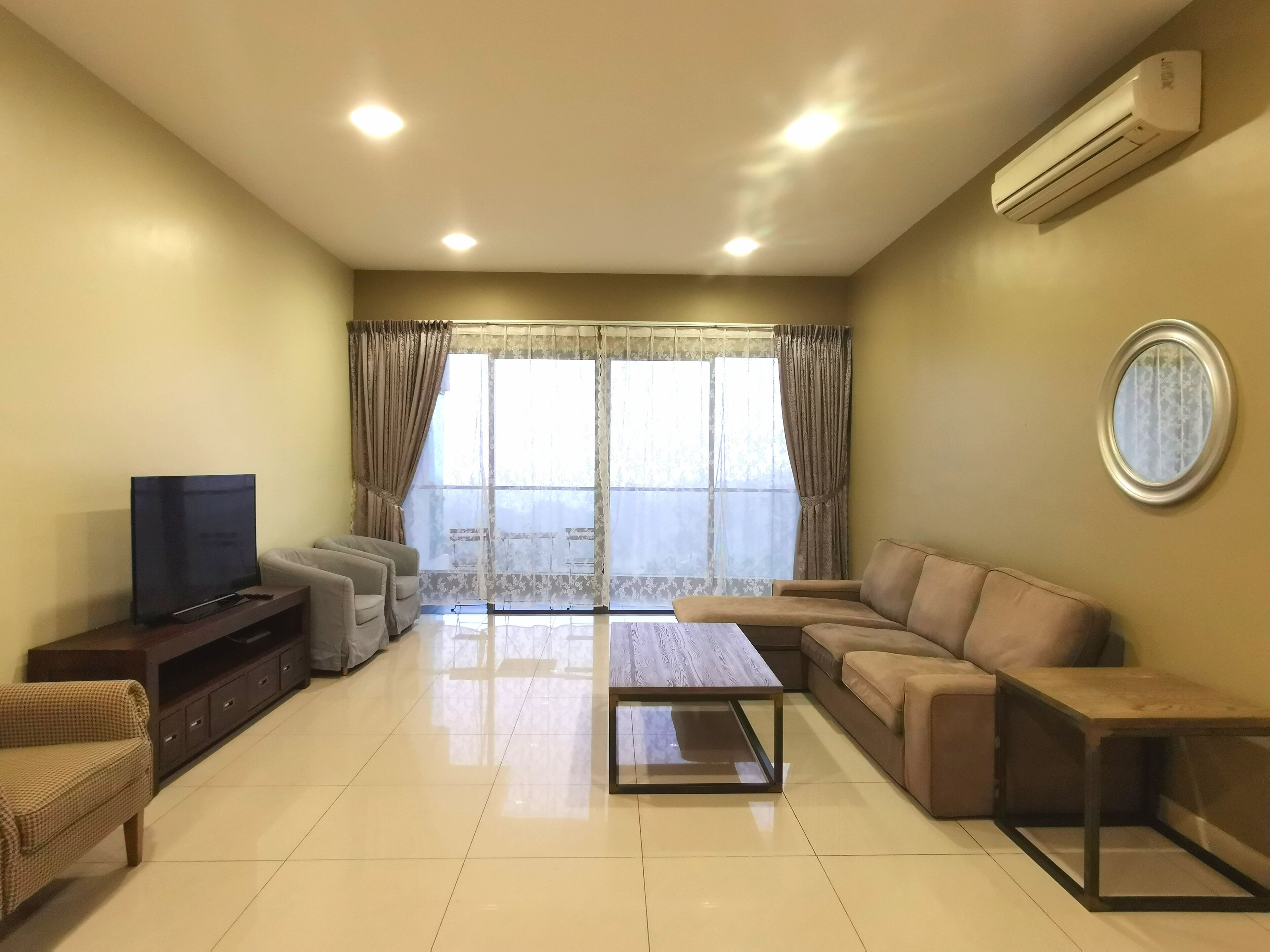 A living room with a sofa, a coffee table, a TV, and a window with curtains.