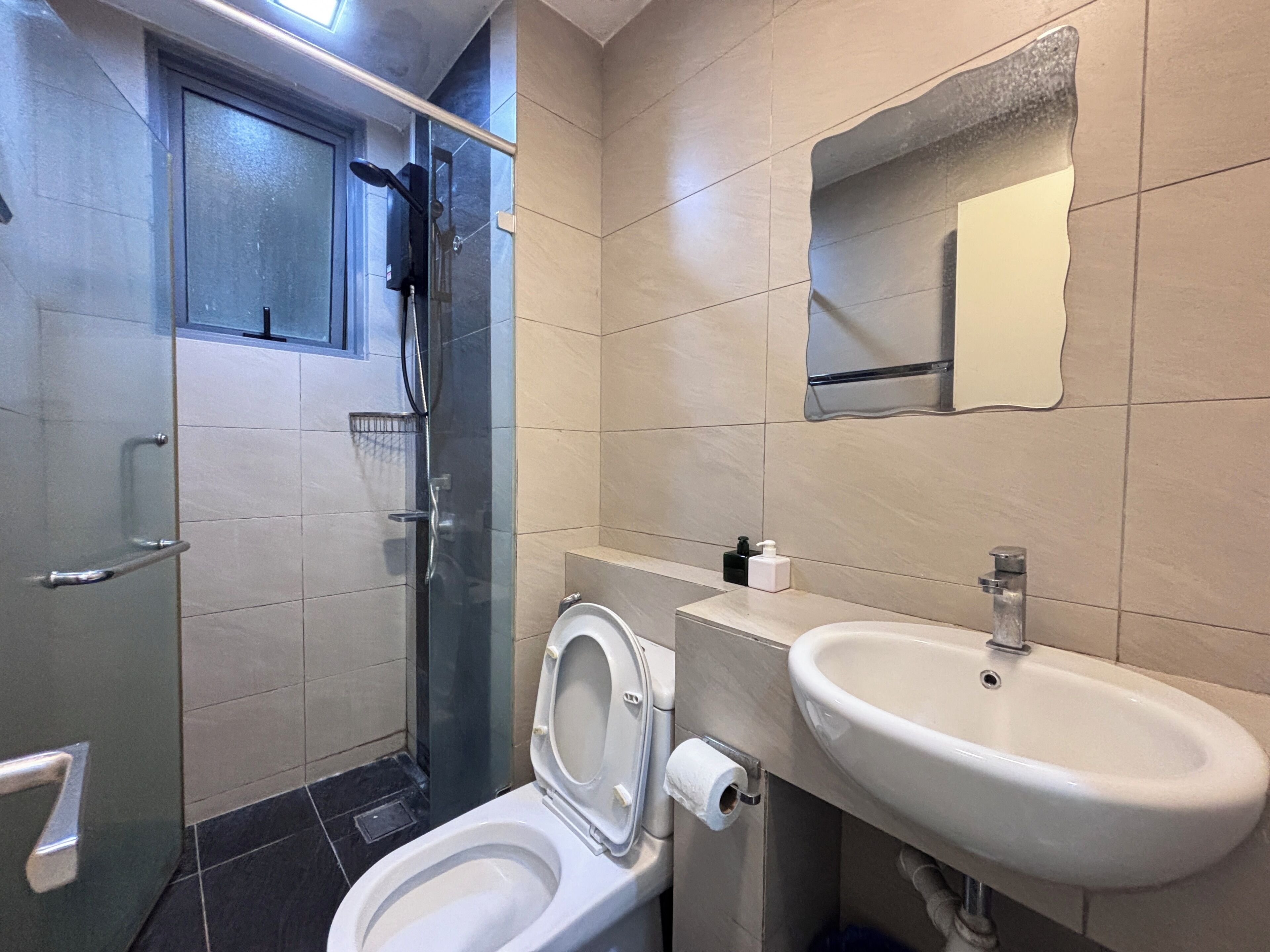 A modern bathroom with a toilet, sink, and glass-enclosed shower.