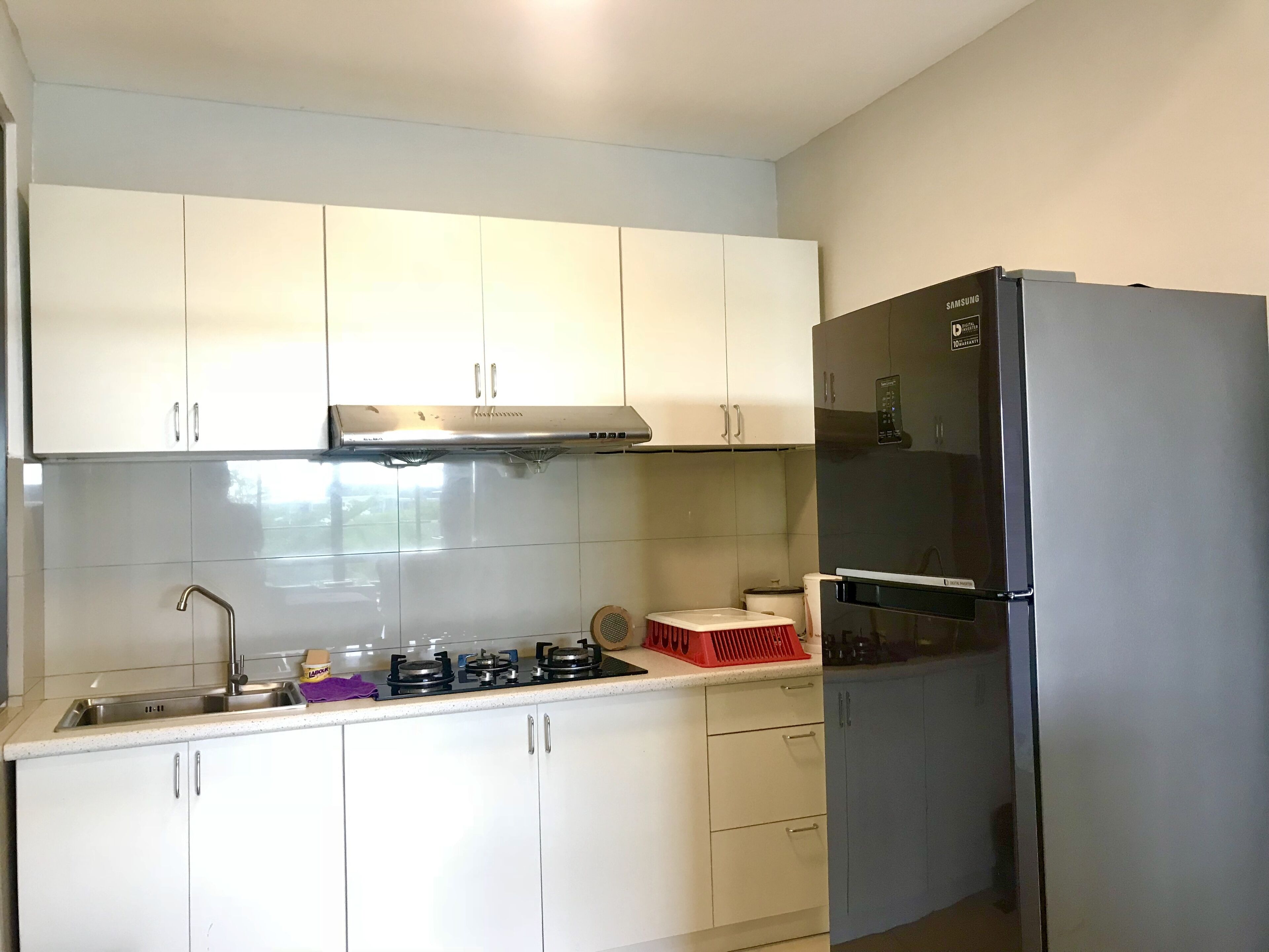 A compact kitchen with white cabinets, a stainless steel range, and a black refrigerator.