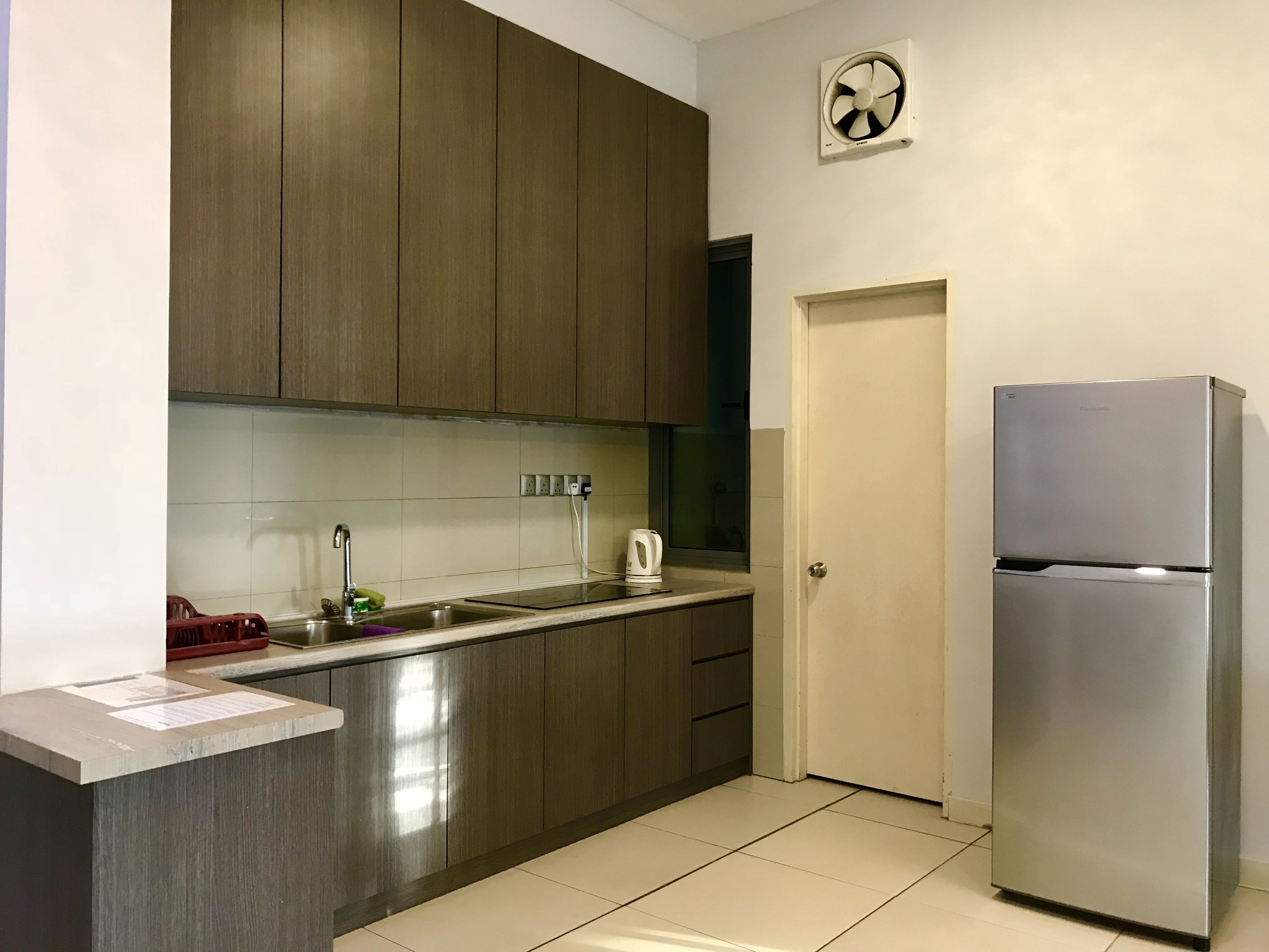 A modern kitchen with dark wooden cabinets, a stainless steel refrigerator, and a tiled backsplash.