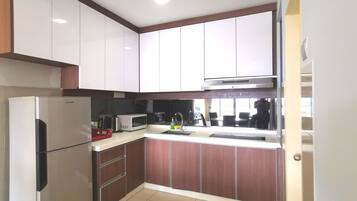 A compact kitchen with white and brown cabinets, a stainless steel refrigerator, a microwave, and a sink.