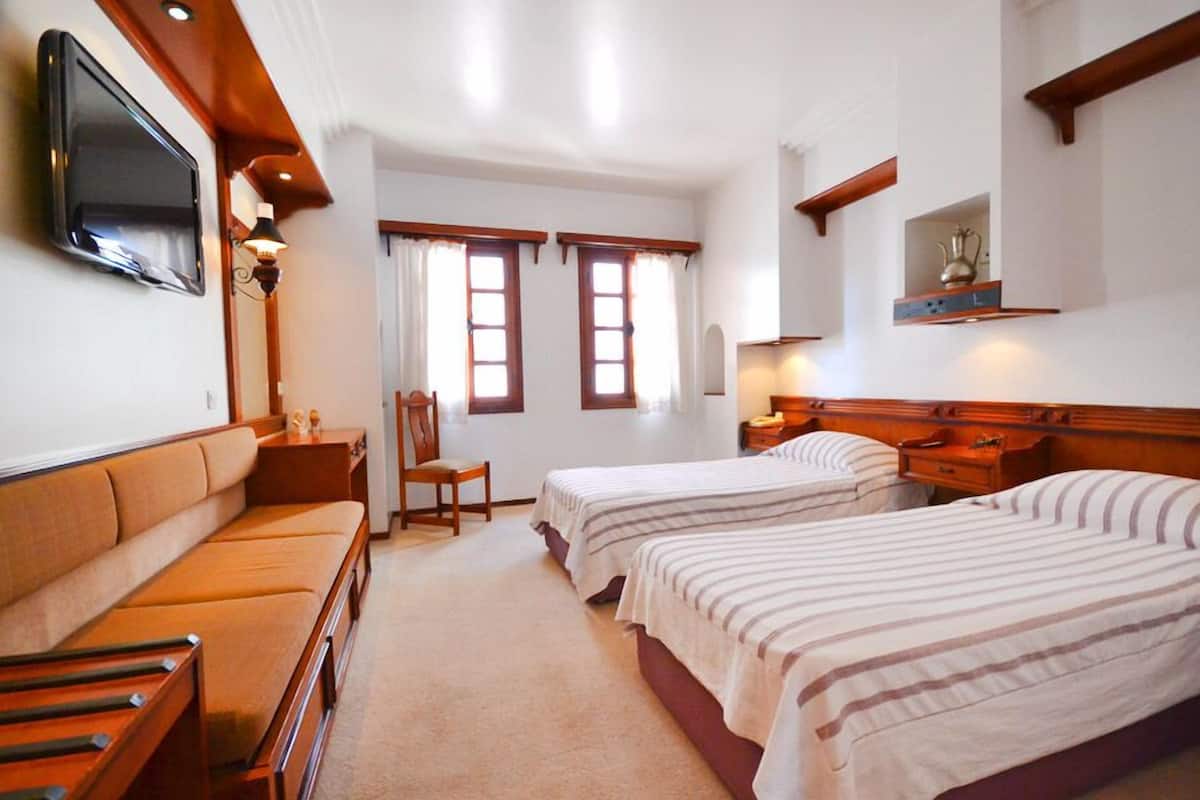 Una habitación de hotel con dos camas, un sofá, un televisor y una mesita.