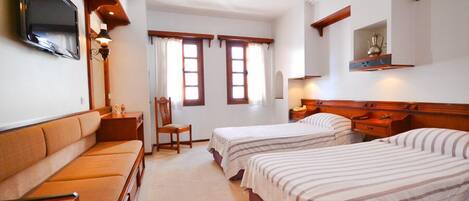 A hotel room with two beds, a sofa, a TV, and a small table.