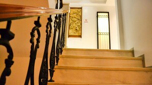 Un escalier orné de rampes noires et d’une main courante en bois, menant à une pièce dotée d’une porte et d’une œuvre d’art accrochée au mur.