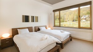 A bedroom with two beds, a large window, and a wall-mounted artwork. - Hana & Jo (Kutchan)