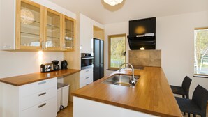 A modern kitchen with wooden countertops, a built-in oven, a stainless steel sink, and a black range hood. - Hana & Jo (Kutchan)