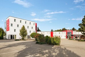 A modern hotel with a white facade, a red accent wall, and a clear sky. - SLEEEP Hotel Sattledt (Sattledt)
