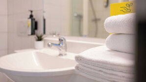 Une salle de bain avec un lavabo, un miroir et une pile de serviettes blanches.