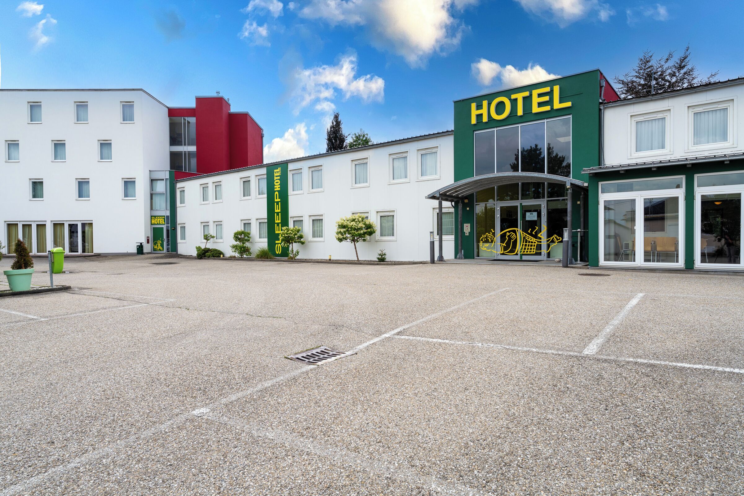 Un hôtel dont l’entrée est bien visible, qui possède de nombreuses fenêtres et un espace de stationnement.