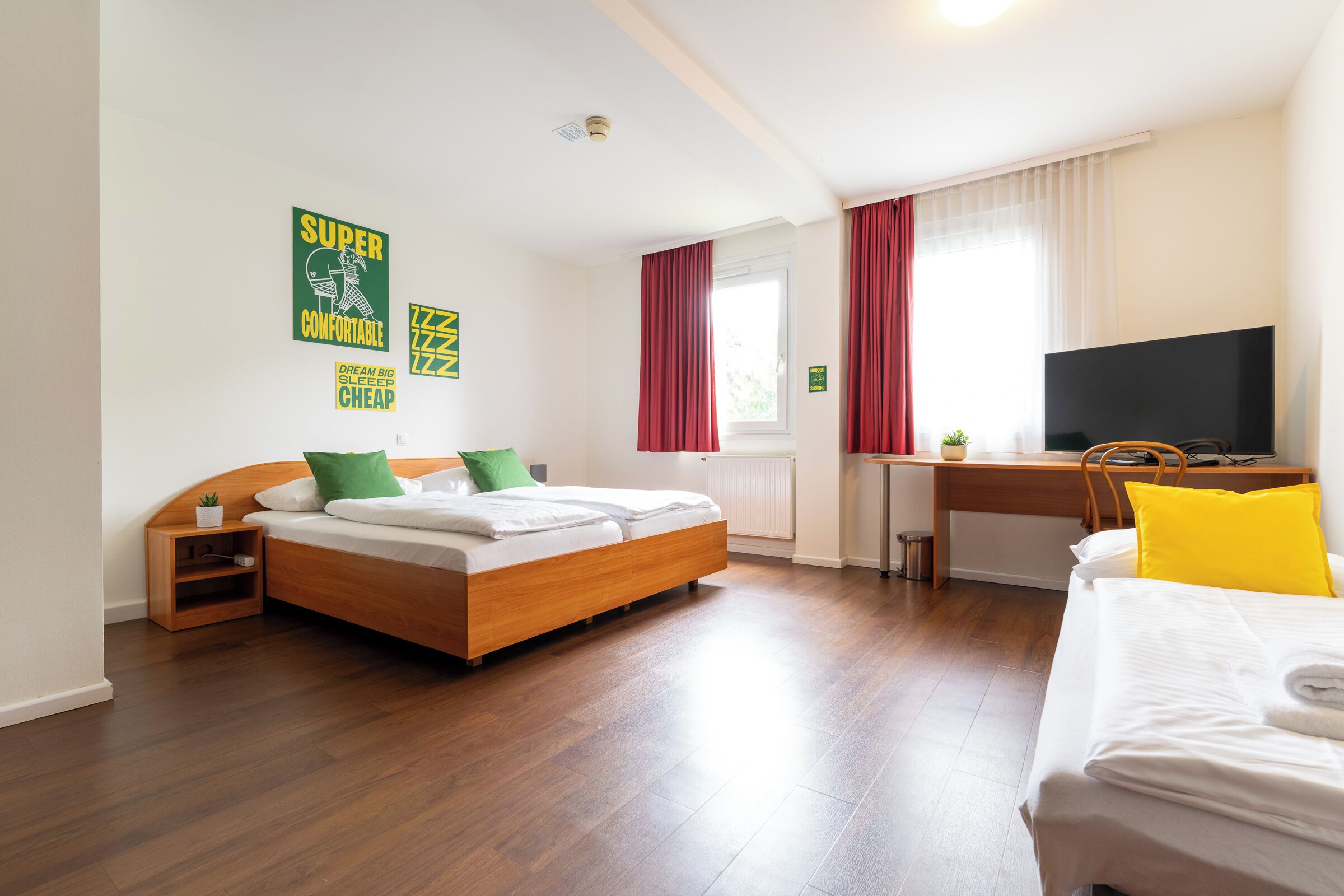 A hotel room with a bed, a desk, a TV, and a window with curtains.