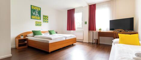 A hotel room with a bed, a desk, a TV, and a window with curtains.