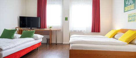 Habitación de hotel con dos camas, un escritorio, un televisor y una ventana con cortinas.