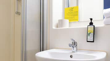 Ein Badezimmer mit Waschbecken, Spiegel, Dusche und einem gelben Schild.