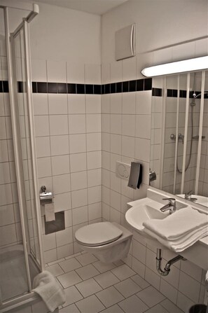 Une salle de bain avec des toilettes, un lavabo et une douche.