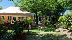 An outdoor dining area with a covered pavilion, tables, chairs, and a garden path. - Hotel Aretxarte (Zamudio)