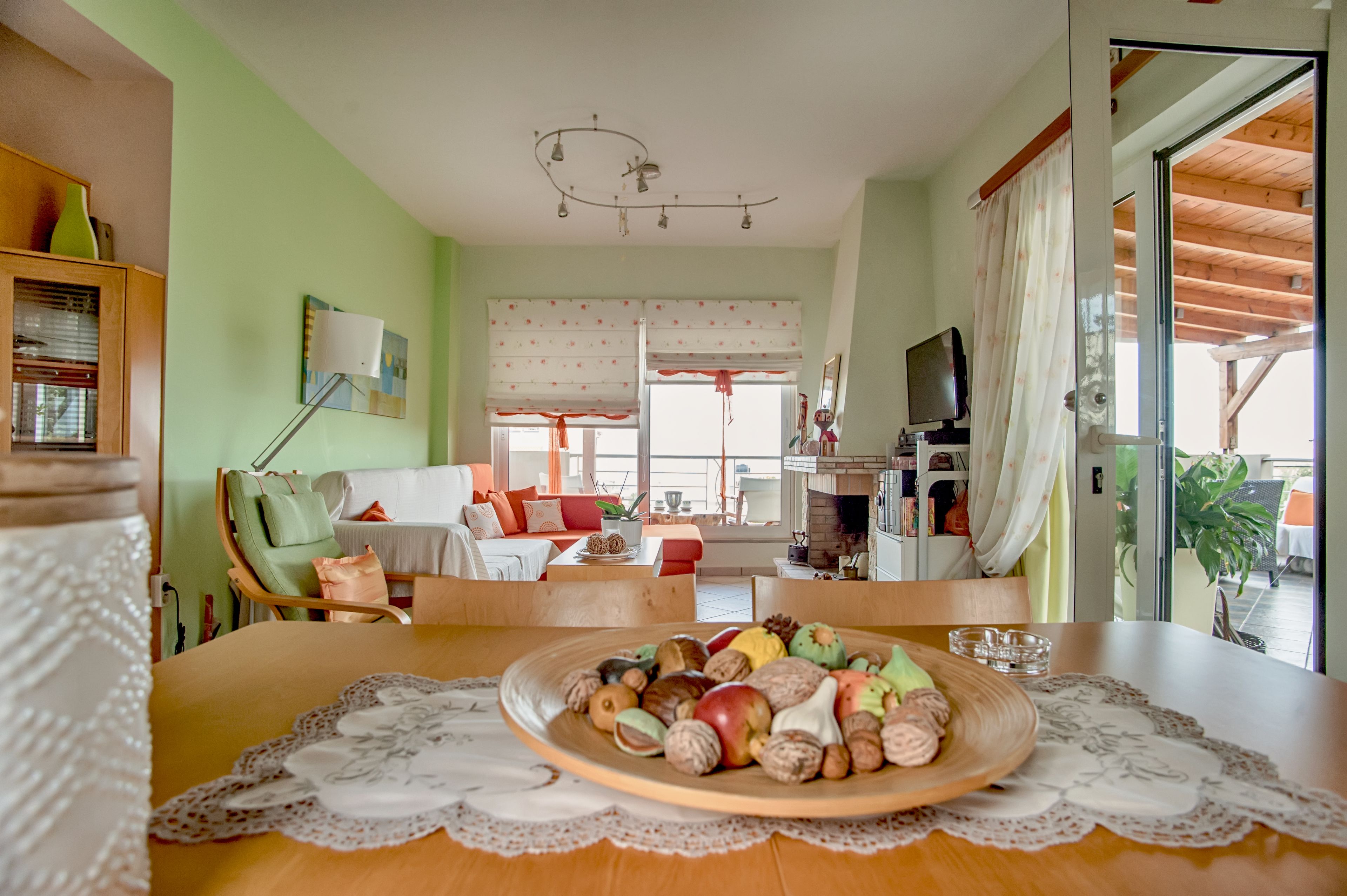A cozy living room with a dining table set with fruits and nuts, a fireplace, and a television.