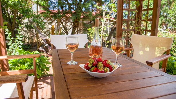 Una mesa de madera con dos copas de vino y un bol de fresas.