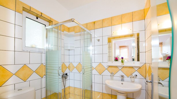 Un baño con ducha de vidrio, lavamanos y espejo.
