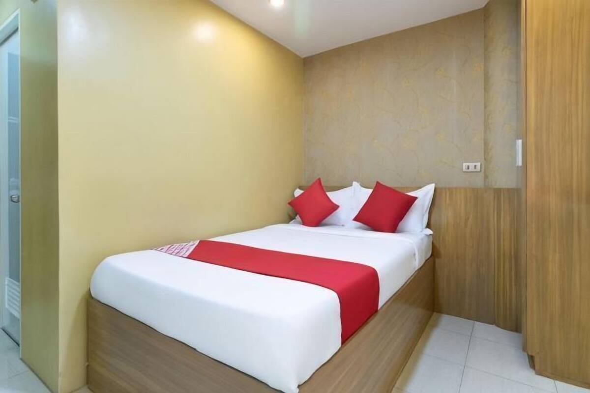 Un dormitorio con cama, cabecero de madera y colcha roja y blanca.