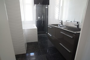 A modern bathroom with a glass shower enclosure, a white toilet, and a vanity with a sink and mirror. - Imperial-Apartments Schönbrunn (Vienna)