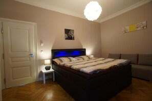 A bedroom with a bed, bedside table, lamp, and a sofa. - Imperial-Apartments Schönbrunn (Vienna)