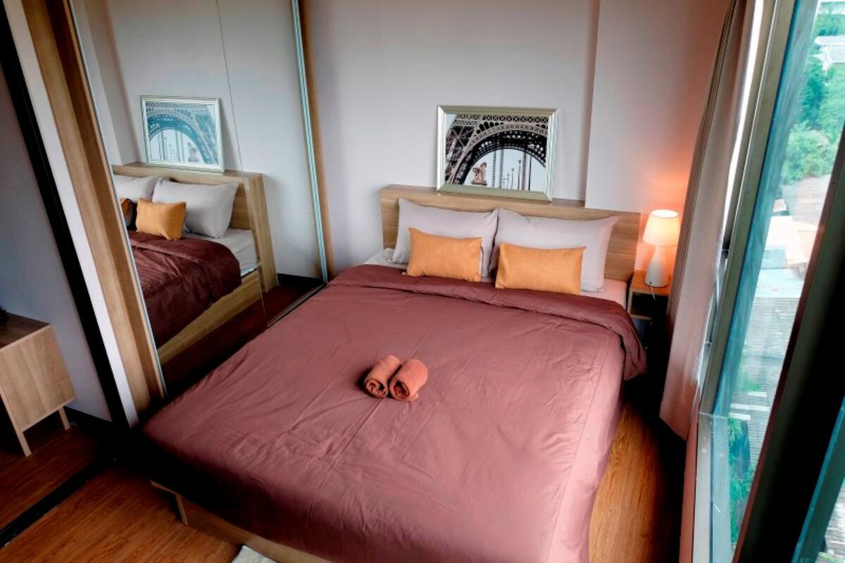 Quarto de hotel com uma cama grande, duas mesas de cabeceira e uma janela com vista.