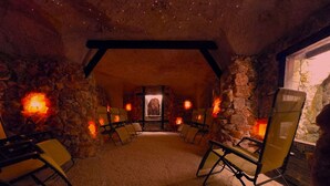 Habitación con paredes de piedra, chimenea, zona de estar y una pared de piedra con ventana.