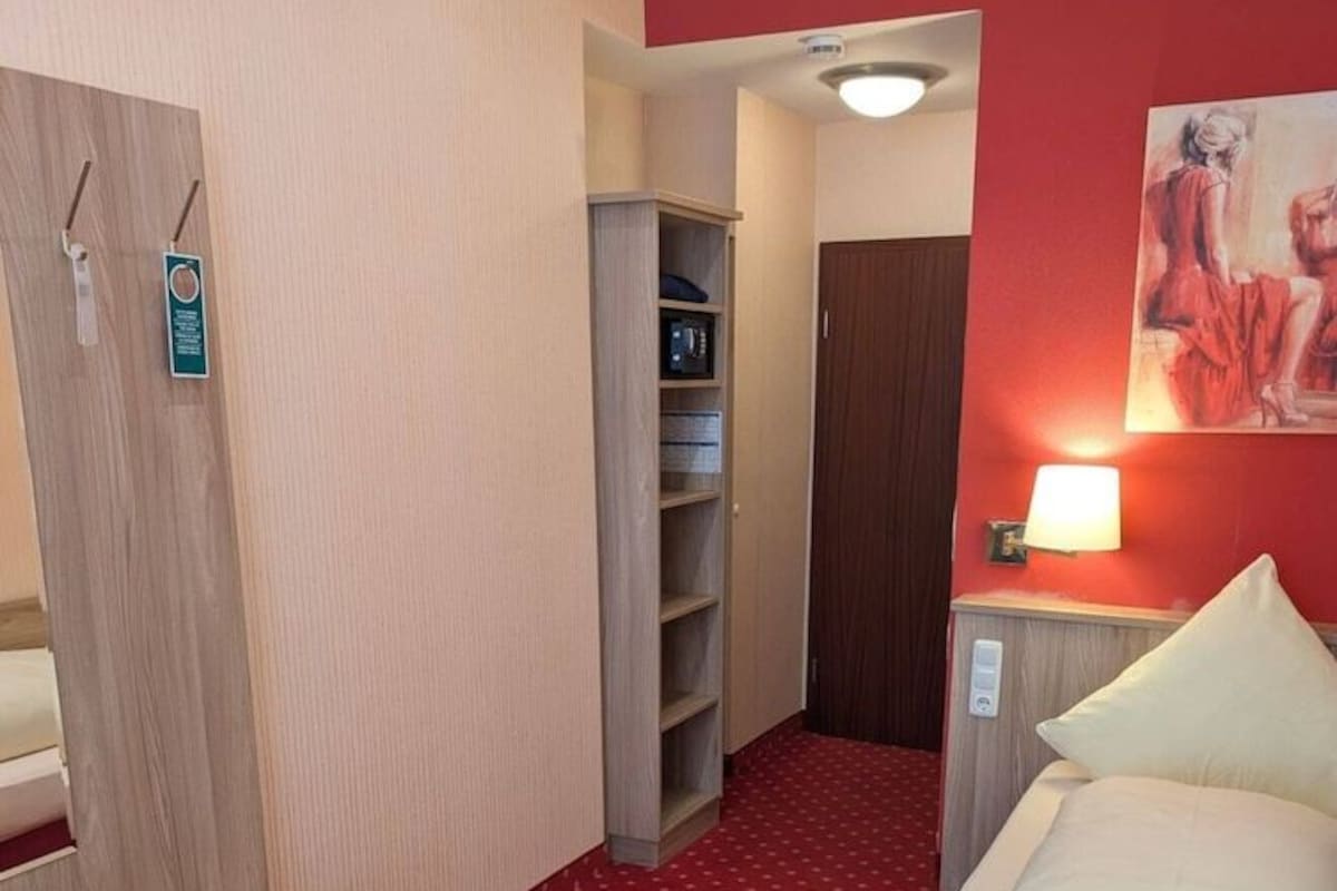 Ein Hotelzimmer mit einem Bett, einem Schreibtisch, einem Kleiderschrank und einem roten Teppichboden.