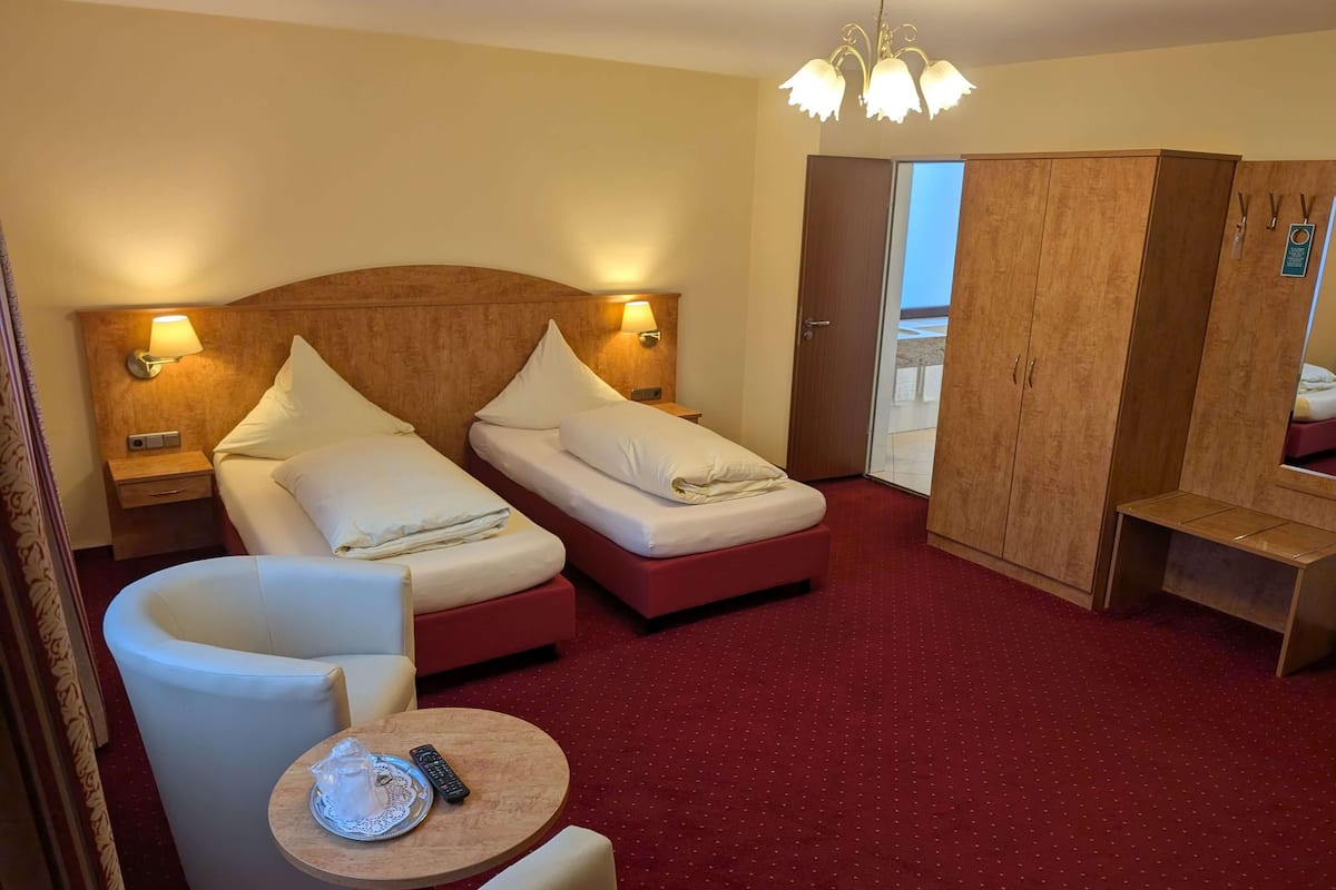 A hotel room with two beds, a sitting area, a round table, and a wardrobe.