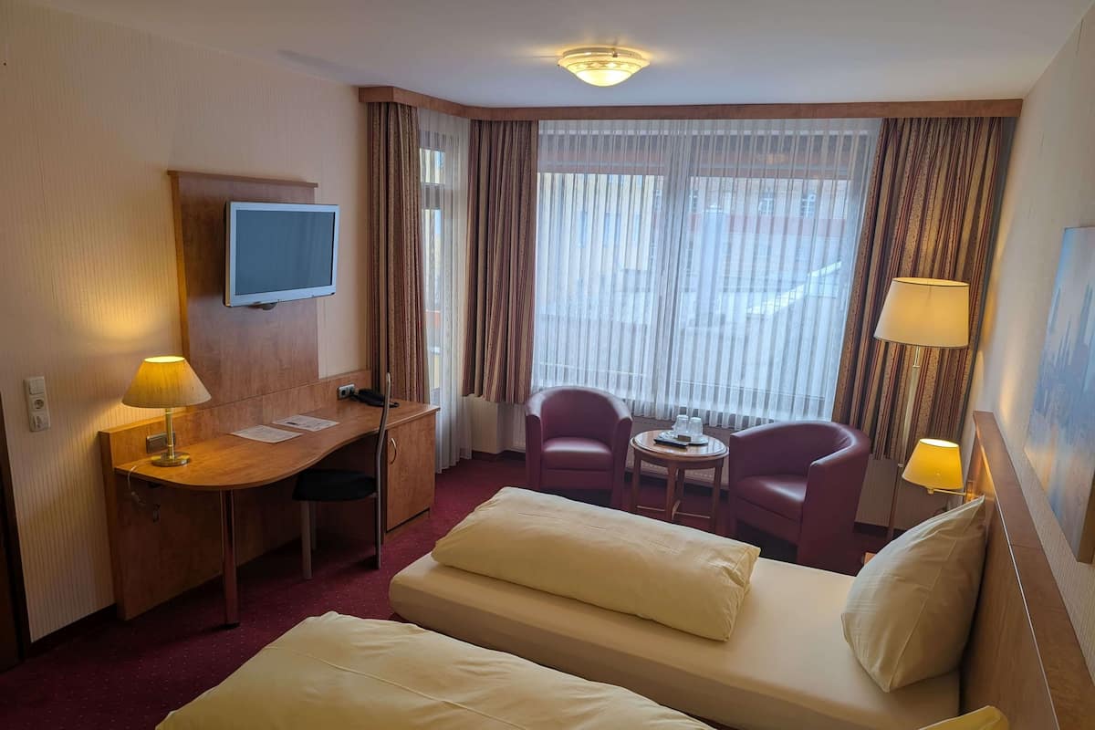 A hotel room with a bed, a desk, a TV, two chairs, and a small table.