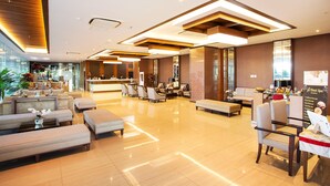 A spacious lobby with a reception desk, seating area, and a modern design with wooden accents and a polished floor. - Tara Hotel Yogyakarta (Yogyakarta)