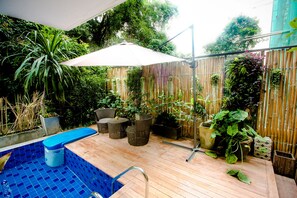 A pool area with a bamboo fence, wicker furniture, and various potted plants. - A Good Nite at Nimman (Chiang Mai)