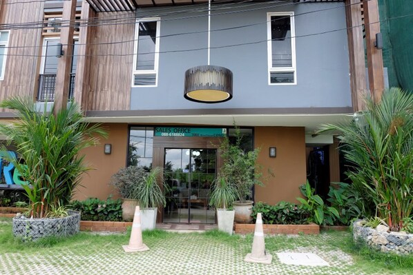A modern building with a sales office entrance, potted plants, and a patterned walkway. - A Good Nite at Nimman (Chiang Mai)